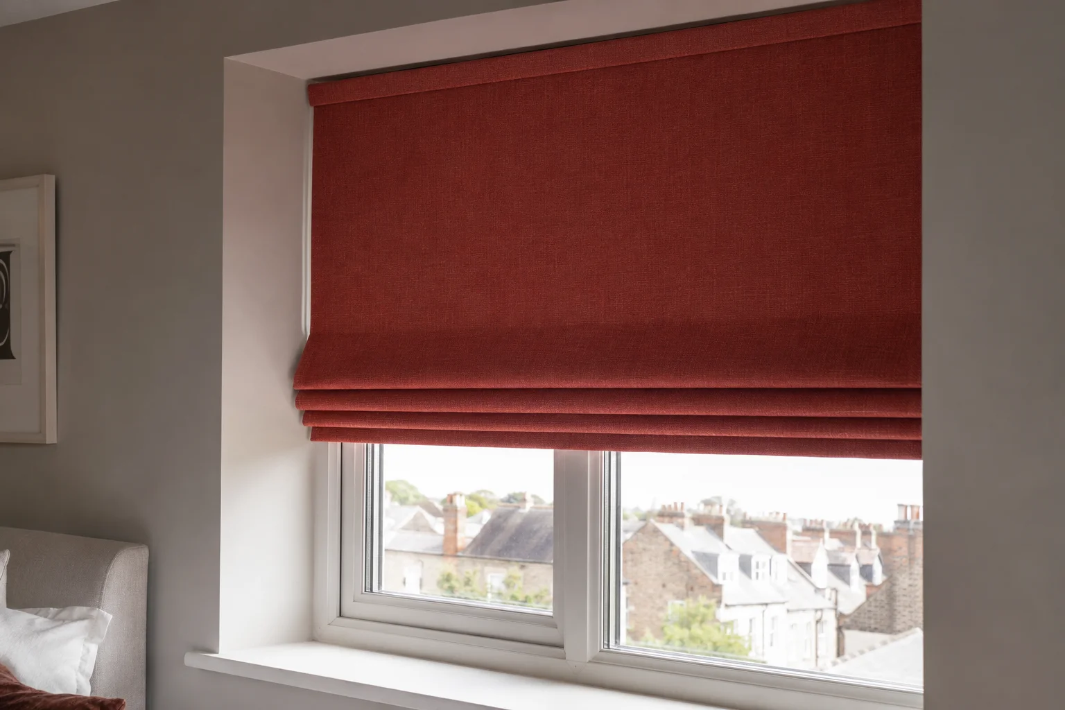 Rust-red Roman blind in daylight bedroom window